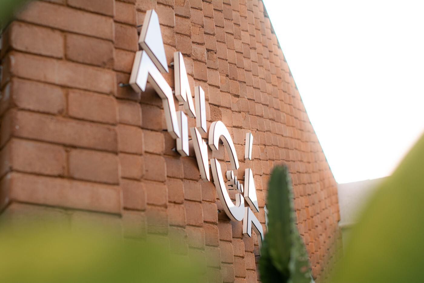 Fachada do Angá Pilates, com o logo na parede de tijolos